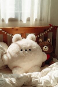 fluffy white and brown stuffed bears laying on bed